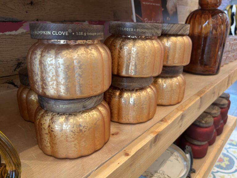 Velas artesanales en tarros dorados sobre una estantería de madera